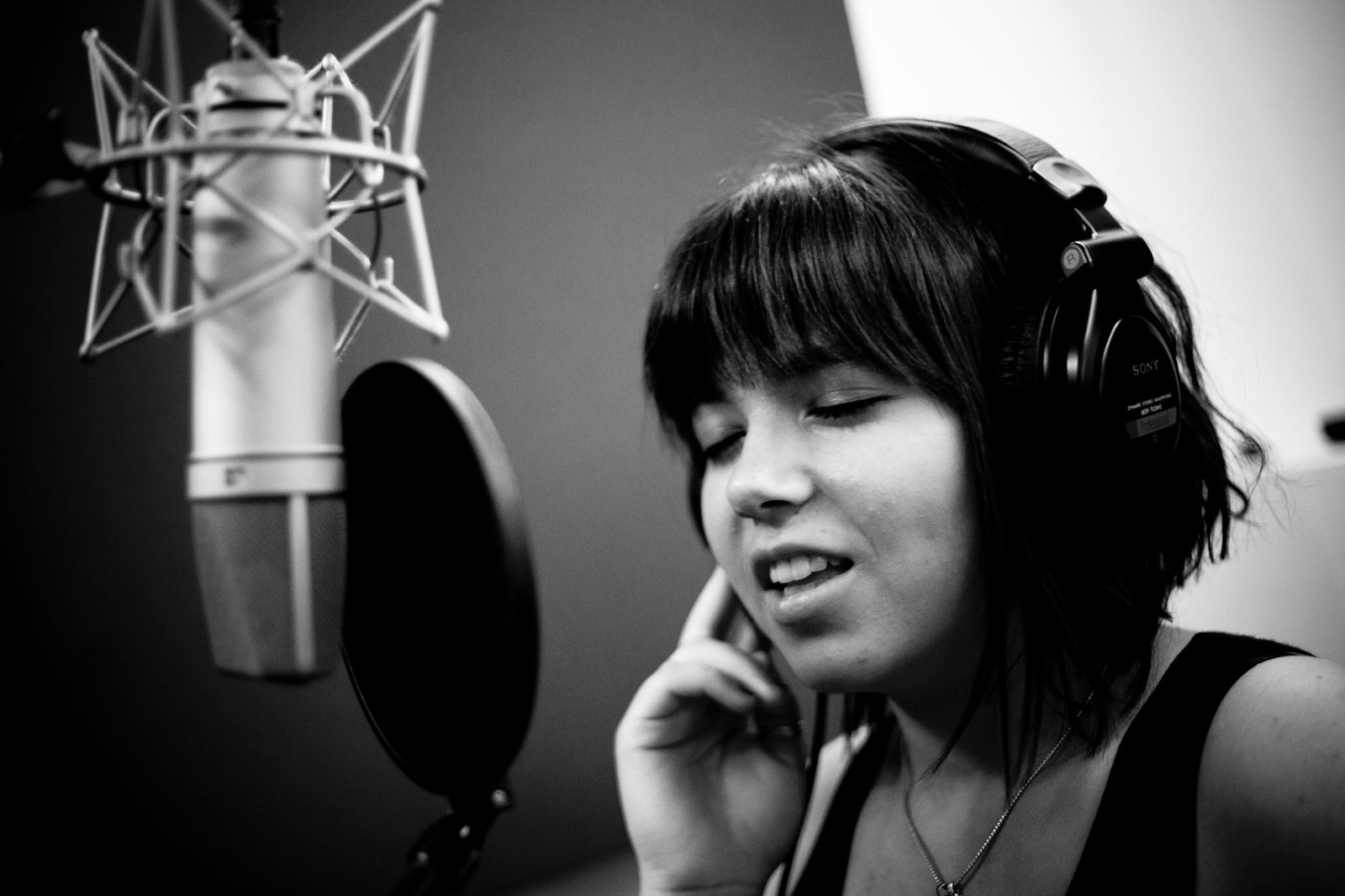 Сайт вокала. А студия певица. Девушка поет. Поет в студии. Фотосессия с микрофоном в студии.
